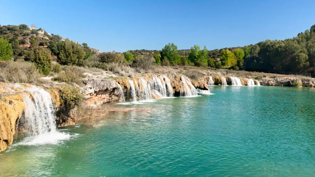 Cascada natural con aguas turquesas y vegetaci&oacute;n exuberante, un oasis inesperado cerca de los pantanos de Madrid.