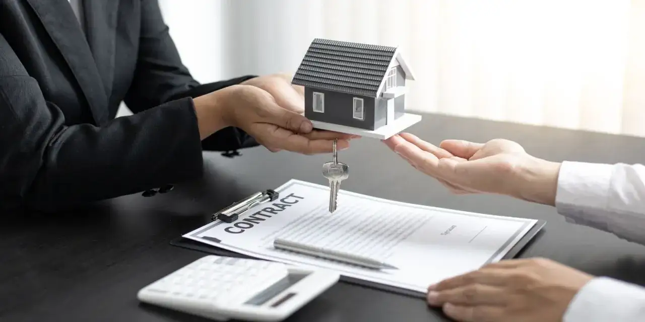 Consegna di una casa modello e chiavi, con contratto e calcolatrice sul tavolo. Un affare di leasing immobiliare privati in corso.