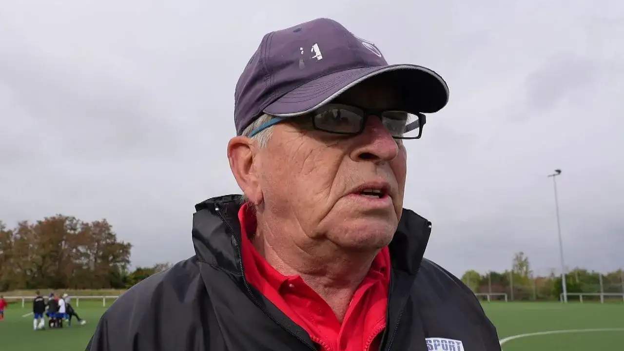 Martin Hoffmann, ein &auml;lterer Mann mit Brille und Kappe, spricht auf einem Fu&szlig;ballplatz.