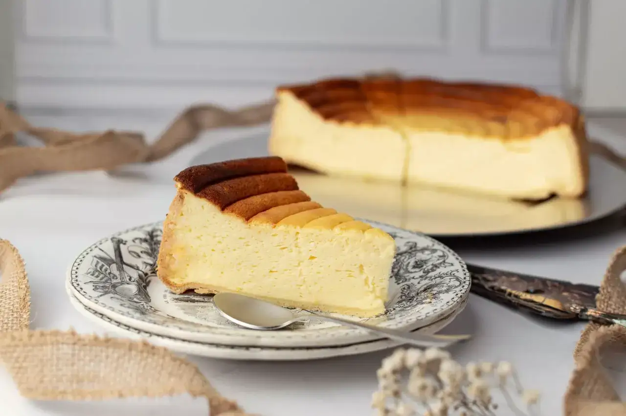 Une part de tarte au fromage, l&eacute;g&egrave;rement caram&eacute;lis&eacute;e, sur une assiette orn&eacute;e. Un d&eacute;lice cr&eacute;meux &agrave; d&eacute;guster.