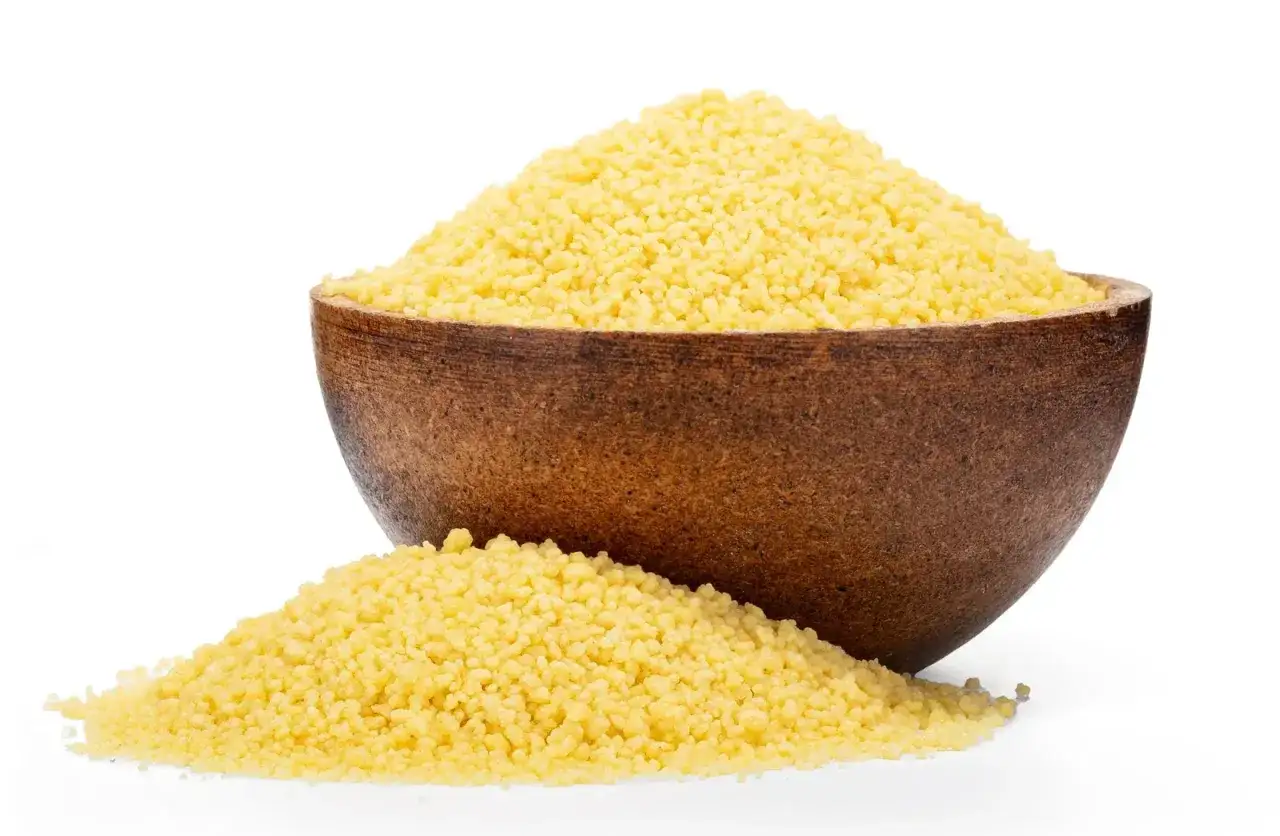 Eine Holzschale gefüllt mit hellem Couscous, daneben ein kleiner Haufen. Ideal für alle, die wissen wollen, ob hartweizen glutenfrei ist.