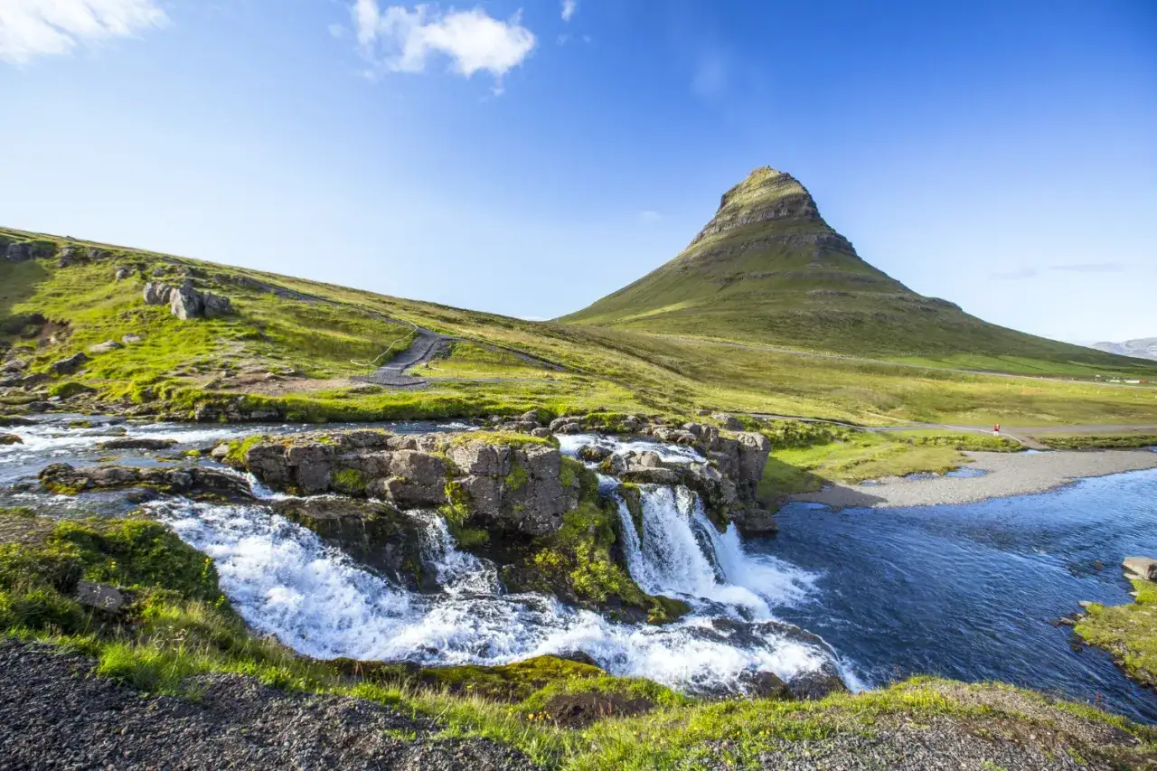 Wodospad Kirkjufellsfoss i góra Kirkjufell. To widok, kiedy jest najcieplej na Islandii, w pełni zieleni i błękitu.
