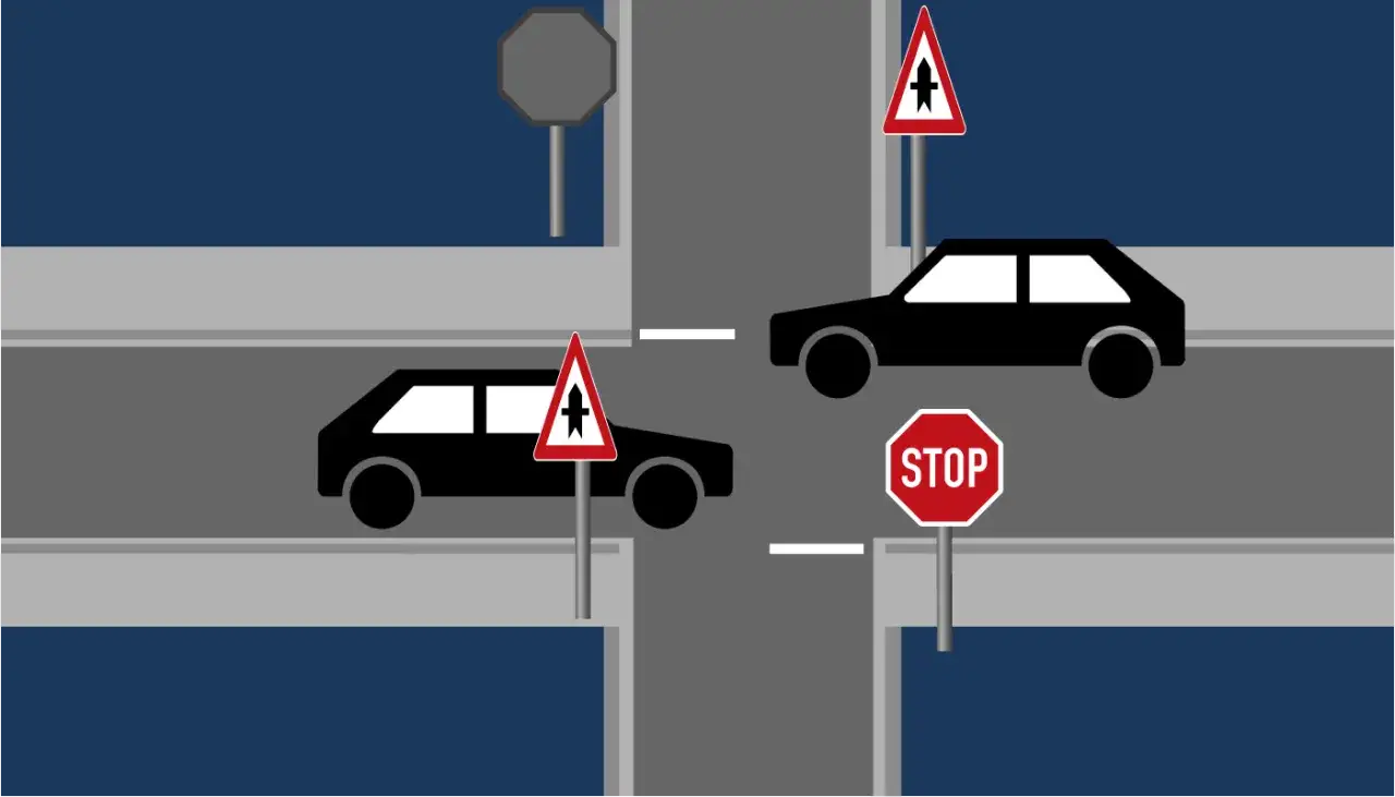 Kreuzung mit Ampel: Wer hat Vorfahrt? Ein Auto wartet an der Stop-Tafel, das andere hat Vorfahrt.