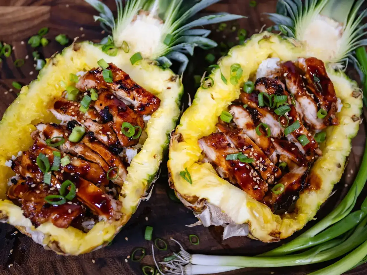 Dos mitades de piña rellenas de arroz y pollo teriyaki, adornadas con cebolleta. ¡Una cena deliciosa que te hará sentir ligero, como si la piña por la noche adelgazara!