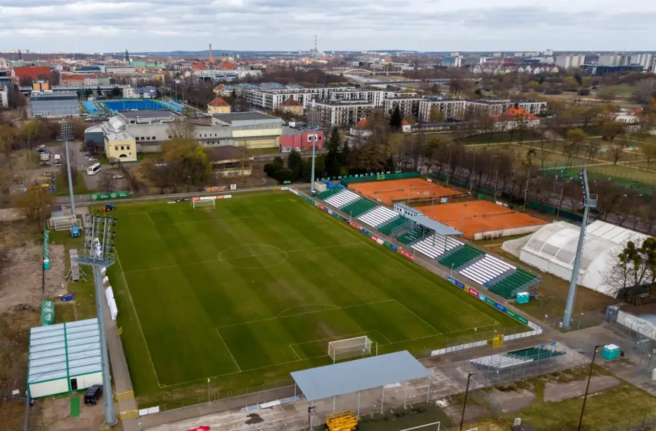Stadion miejski w Poznaniu z boiskiem piłkarskim, kortami tenisowymi i trybunami.