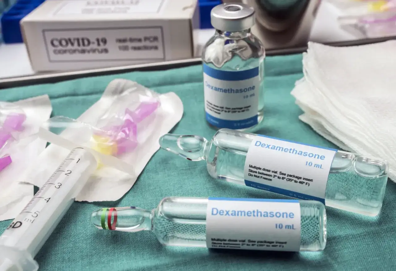 Dwa ampułki i fiolka z lekiem Dexamethasone 10 ml, strzykawka i opakowanie testu COVID-19.