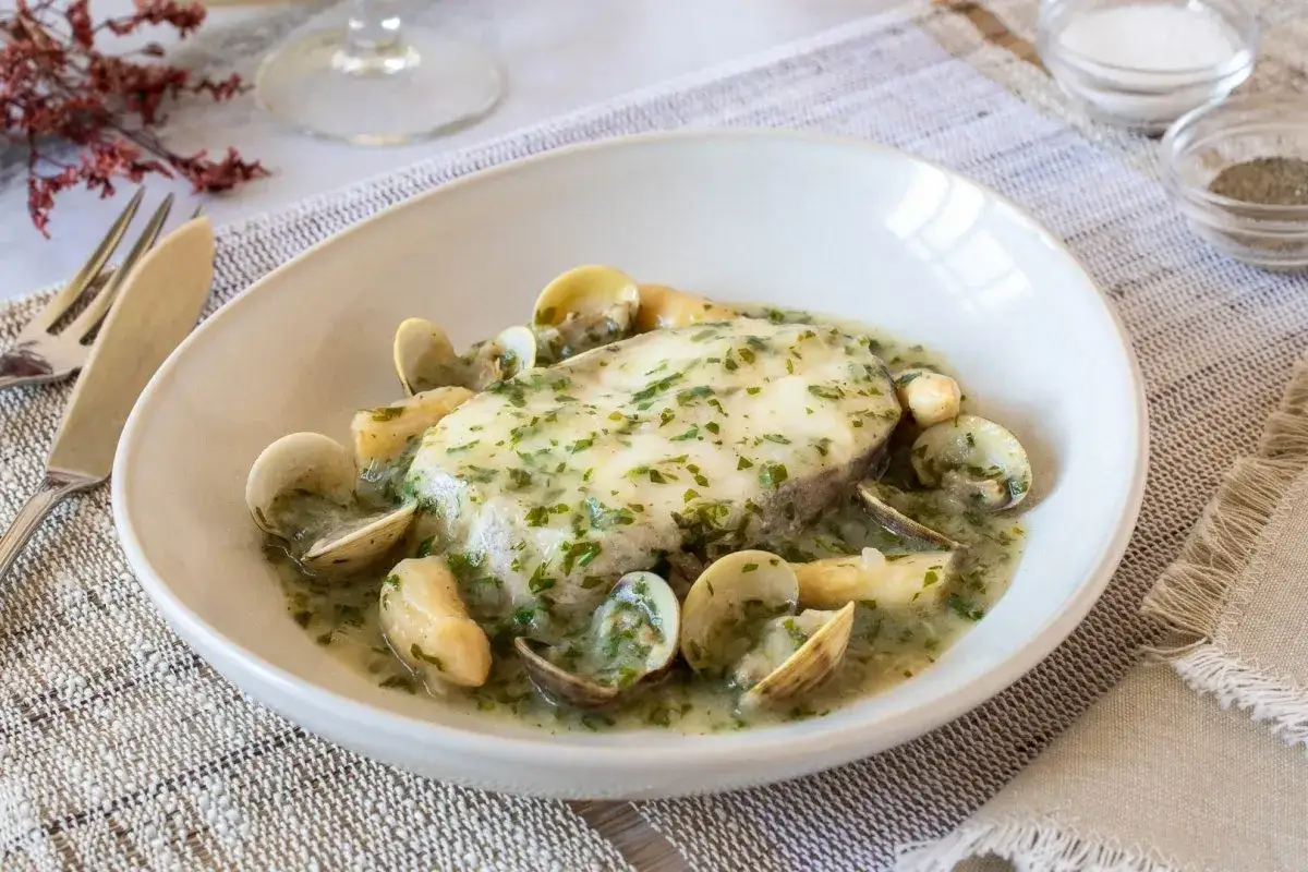 Merluza en salsa verde con almejas, un plato tradicional español que invita a disfrutar de sabores marinos.