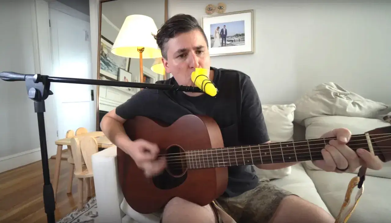 Un homme joue de la guitare et du kazoo musique, créant une mélodie joyeuse dans son salon.