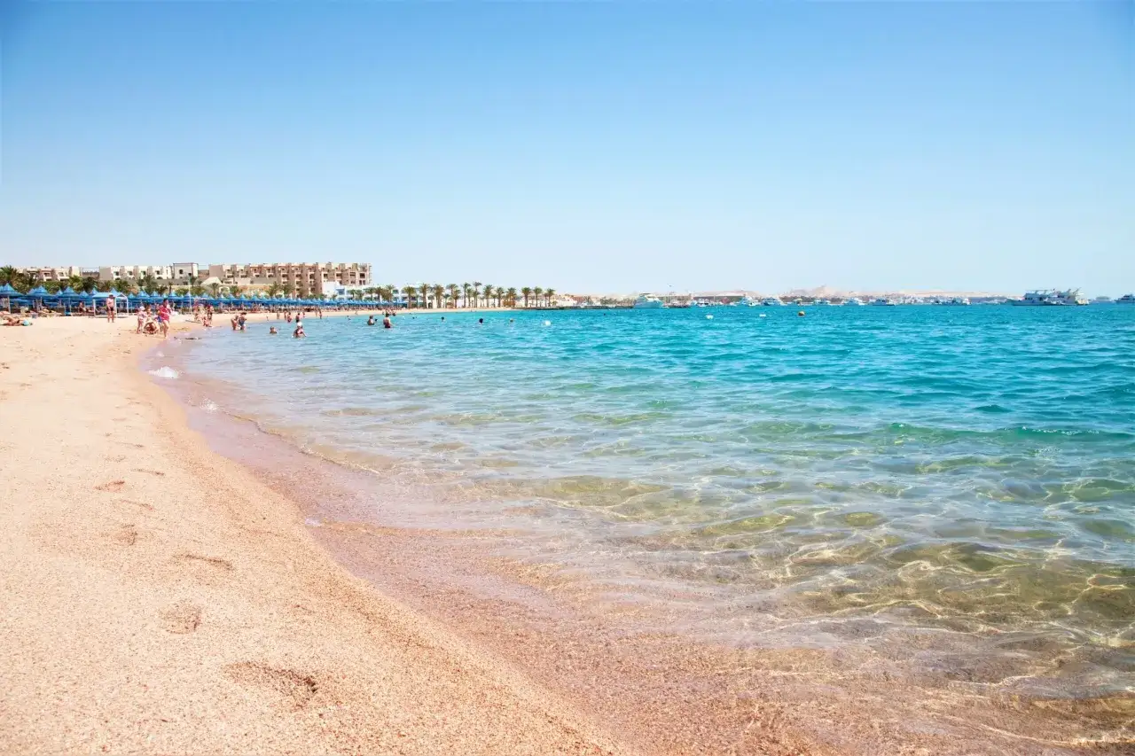 Plaża w Hurghadzie z turystami kąpiącymi się w krystalicznie czystej wodzie. Czy Hurghada jest bezpieczna? Tłumy ludzi i spokojna atmosfera sugerują, że tak.