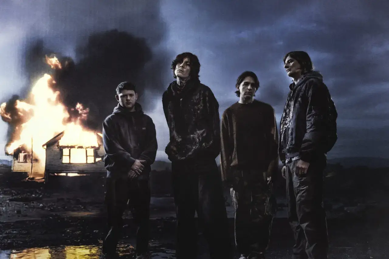 Członkowie Bring Me The Horizon stoją na tle płonącego domu.