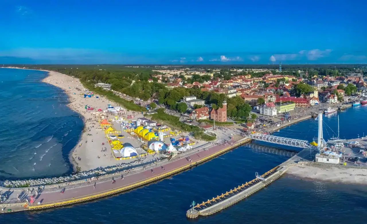 Urokliwe ustka atrakcje: plaża, port, miasteczko z czerwonym ratuszem i mn&oacute;stwo ludzi cieszących się latem.