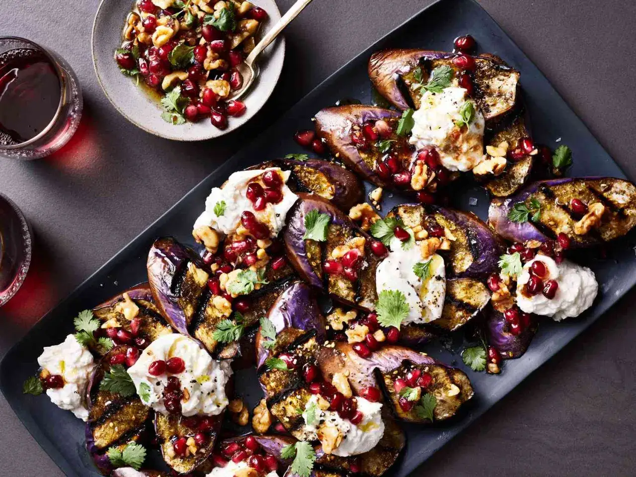 Gegrillte Auberginenspalten mit cremiger Burrata, Granatapfelkernen und Walnüssen – eine köstliche Inspiration für Burrata Rezepte.