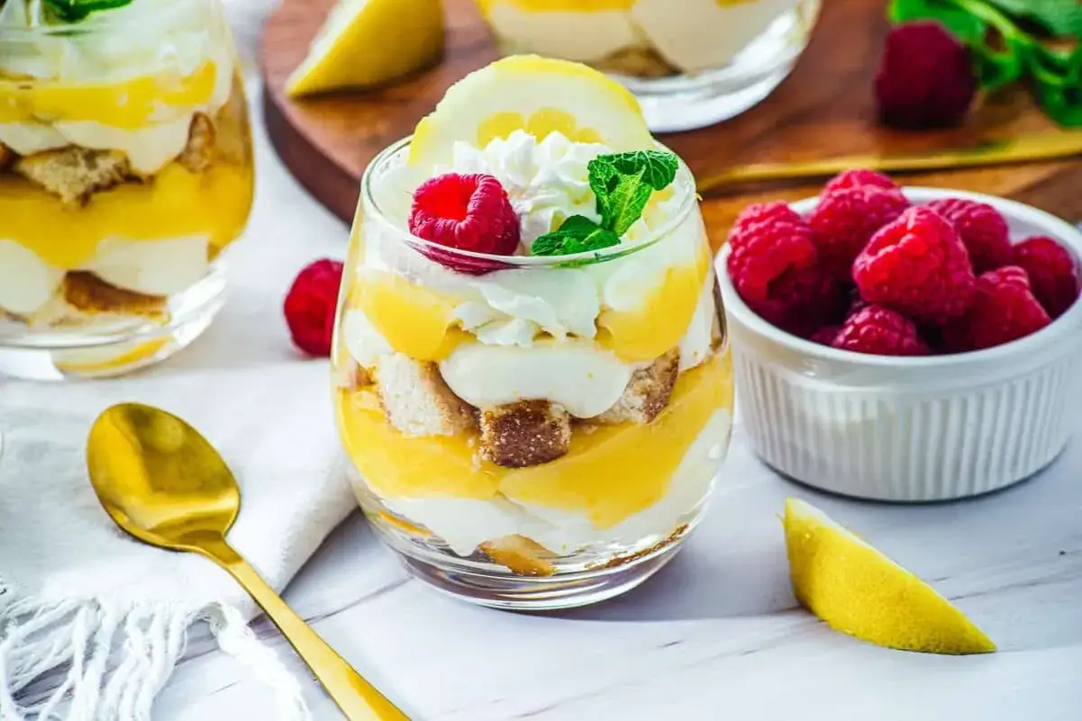 Erfrischendes Zitronen-Dessert im Glas mit Biskuit, Sahne und Himbeeren. Ein s&uuml;&szlig;er Genuss f&uuml;r warme Tage.