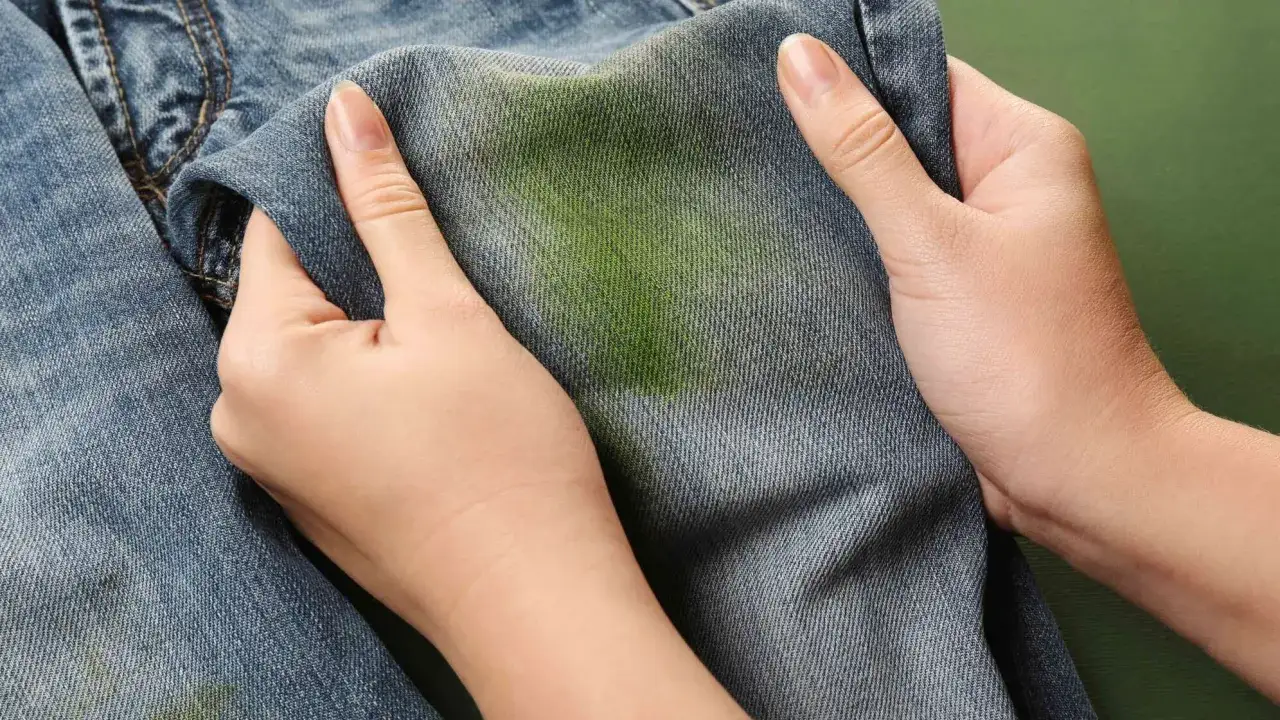 H&auml;nde halten Jeans mit gr&uuml;nen Grasflecken. Tipps zum Grasflecken entfernen.