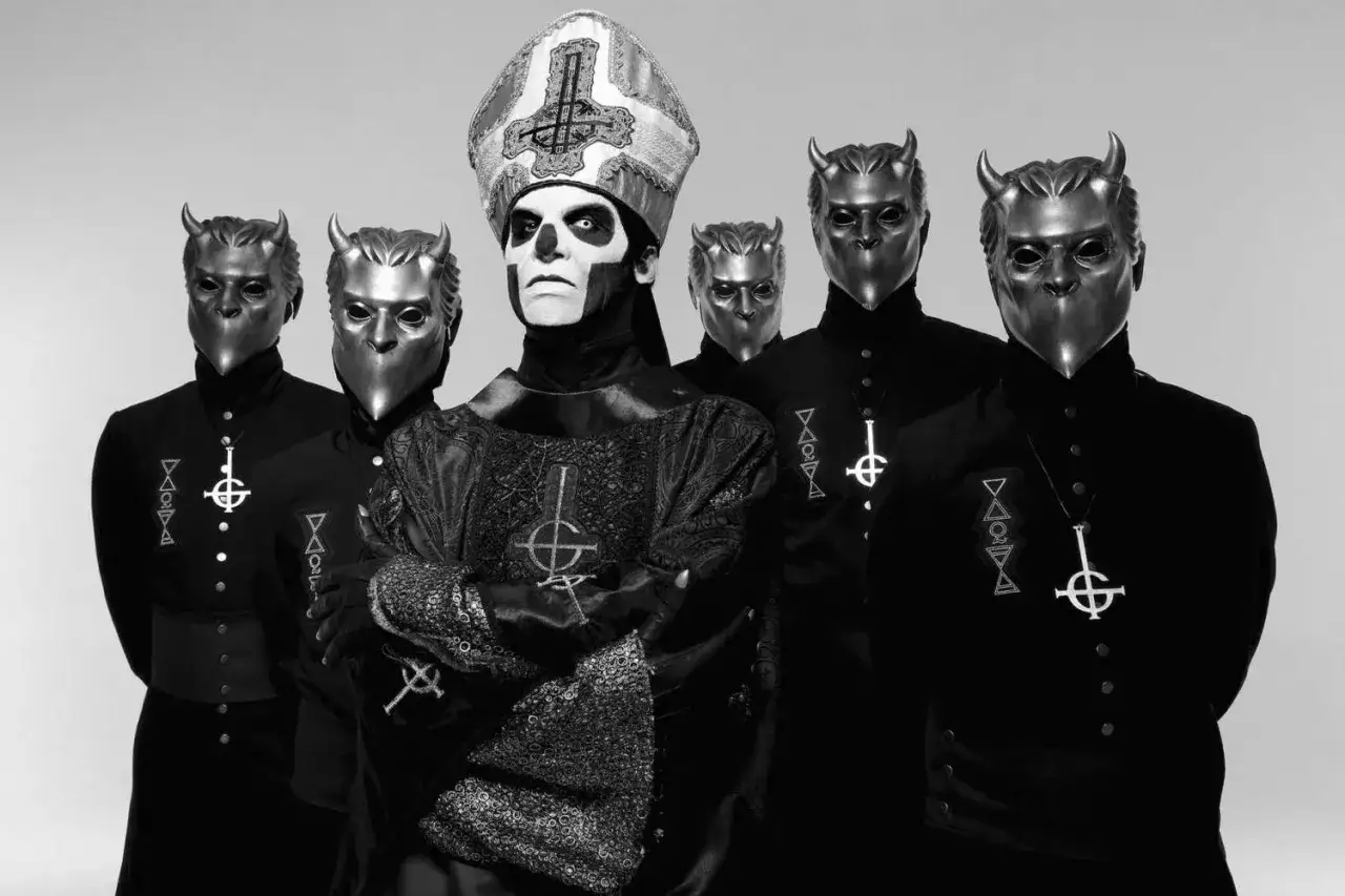 Papa Emeritus III w otoczeniu pięciu tajemniczych postaci w maskach z rogami.