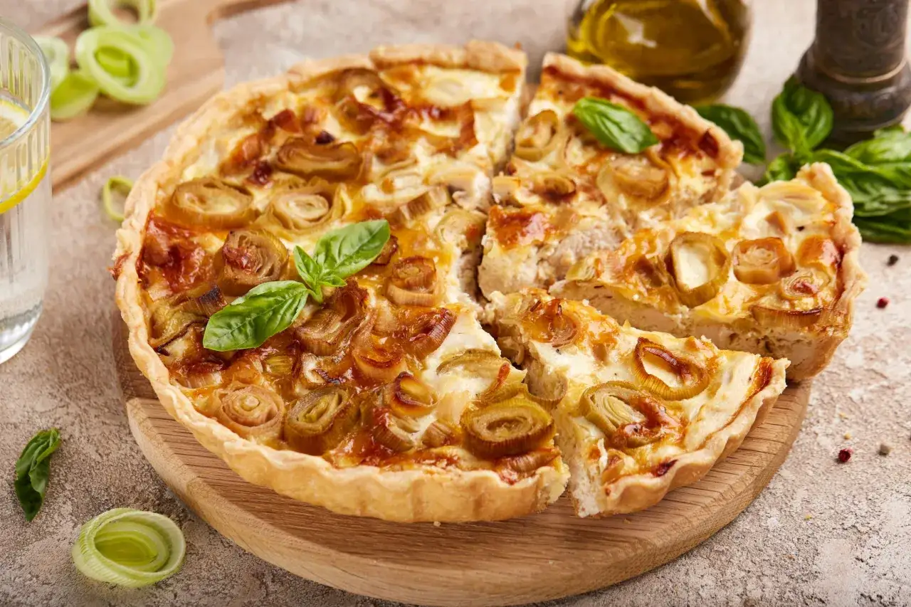 Une d&eacute;licieuse tarte aux poireaux &agrave; l'ancienne, garnie de poireaux caram&eacute;lis&eacute;s et de feuilles de basilic frais, pr&ecirc;te &agrave; &ecirc;tre d&eacute;gust&eacute;e.
