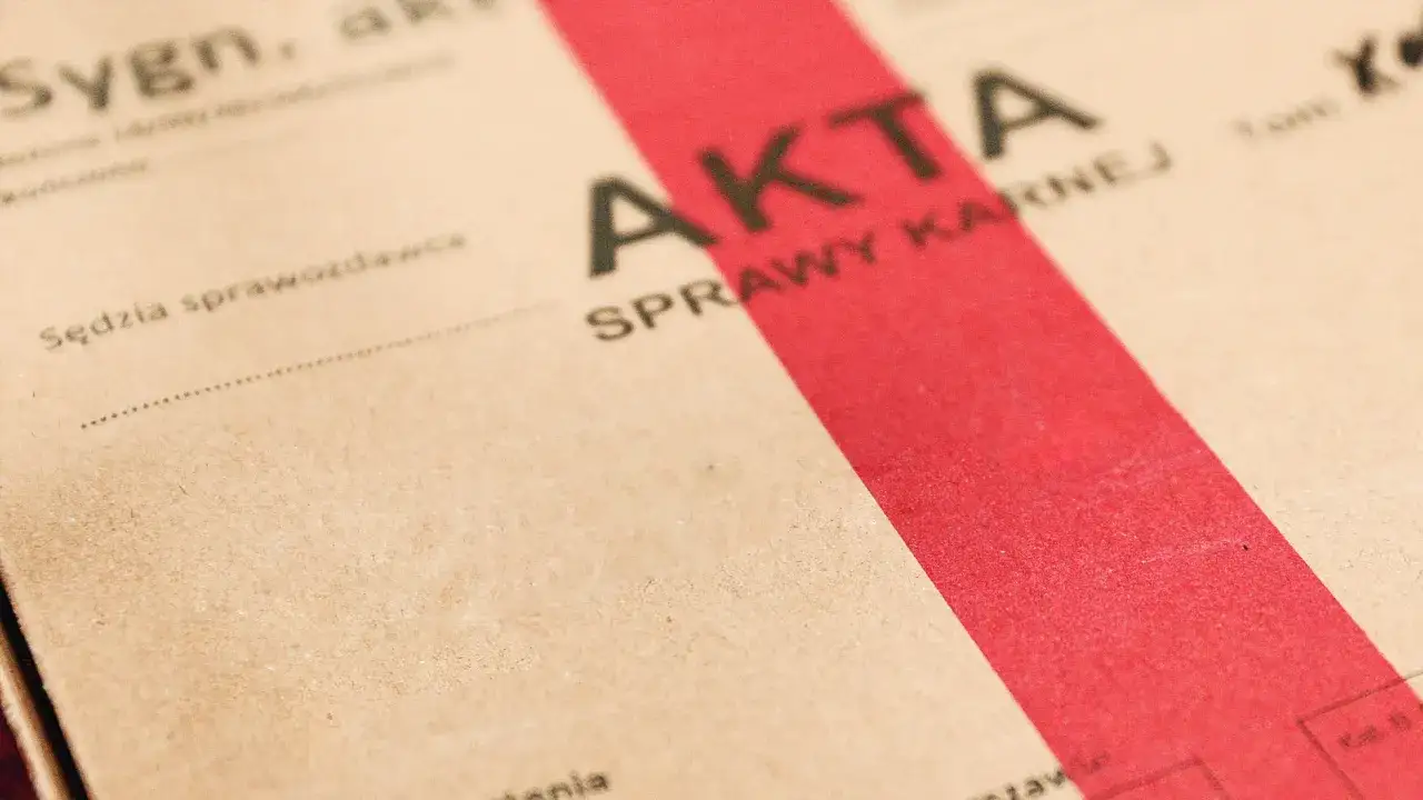 Akta sprawy karnej z czerwoną wstęgą. Może to symbol nadziei na amnestia lub nowy początek.
