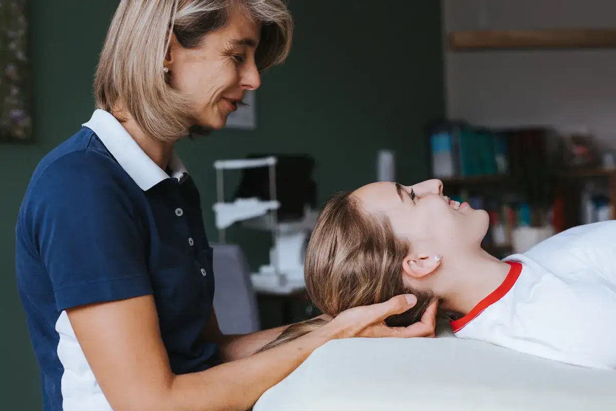 Osteopathin behandelt junge Frau am Kopf. Sanfte Berührung, die zeigt, wie sinnvoll Osteopathie sein kann.