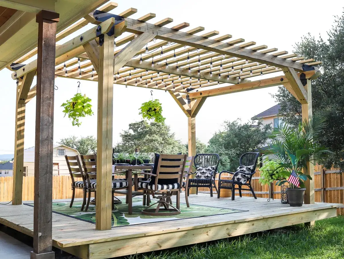 Paso a paso: como hacer una pergola de madera. Deck de madera con mesa, sillas y luces colgantes, ideal para disfrutar el exterior.
