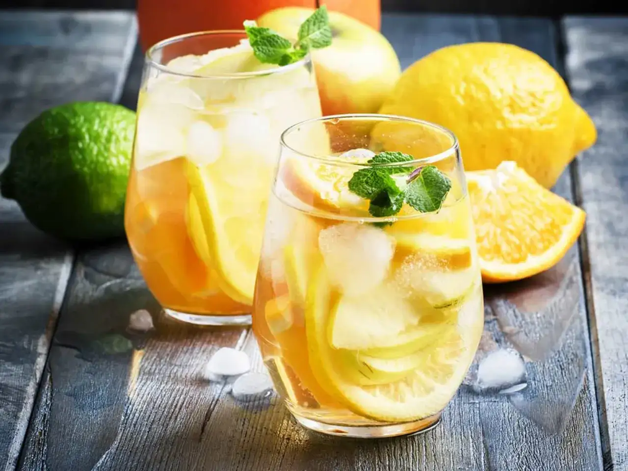 Två glas med uppfriskande vit sangria fyllda med frukt och is. Citroner, apelsiner och äpplen ger en härlig smak.