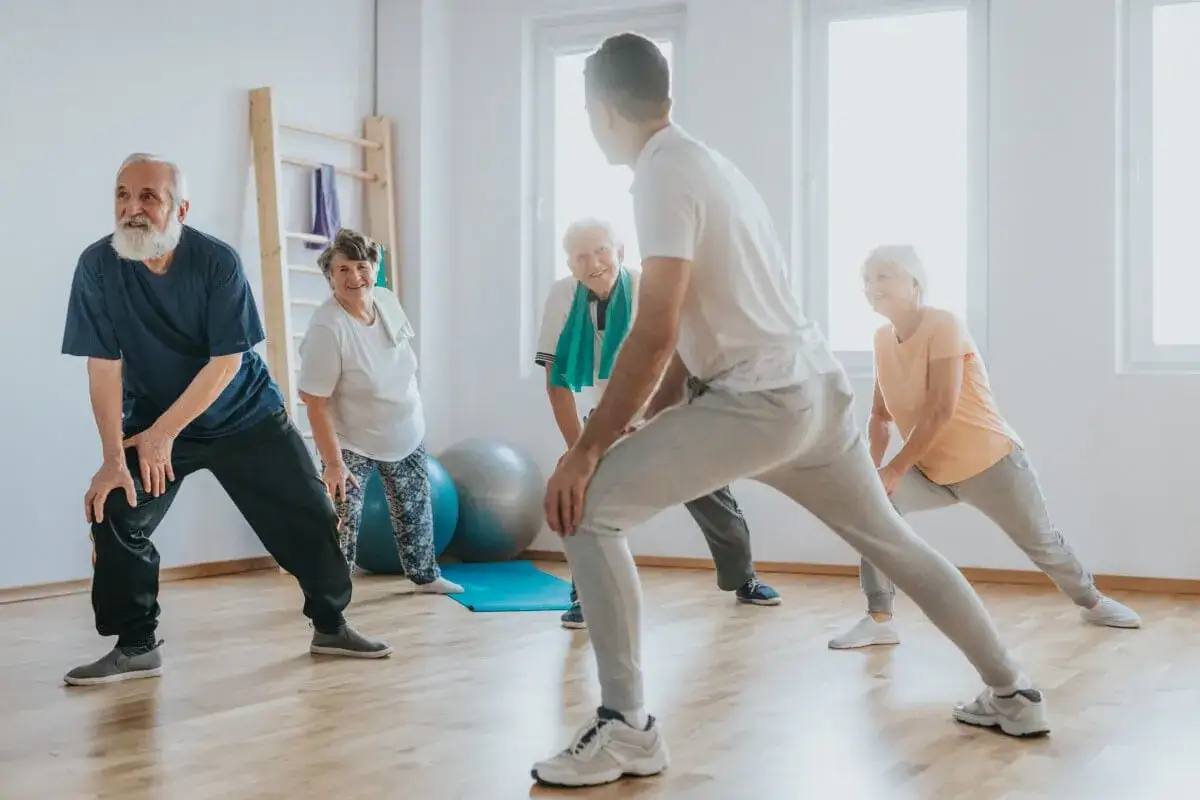 Senioren machen Dehnübungen unter Anleitung eines Trainers, um ihre Gelenkschmiere aufzubauen und fit zu bleiben.