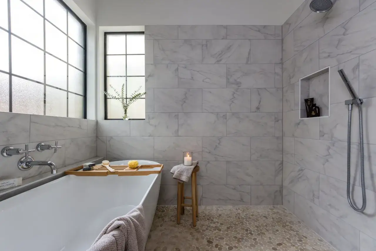 Salle de bain moderne avec baignoire, douche et carrelage 60x120 pose décalée. Sol en galets.