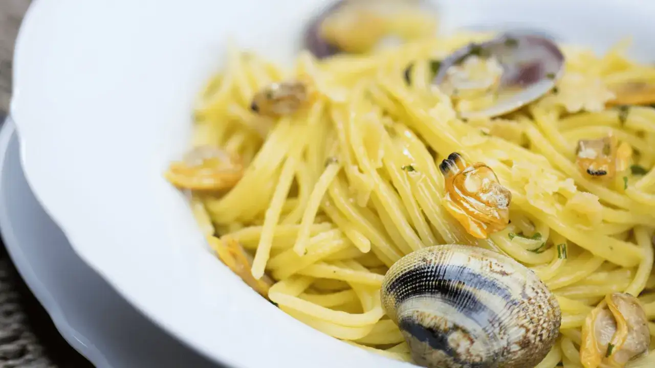Spaghetti dorati con vongole fresche, un classico piatto di pasta con le vongole, pronto per essere gustato.