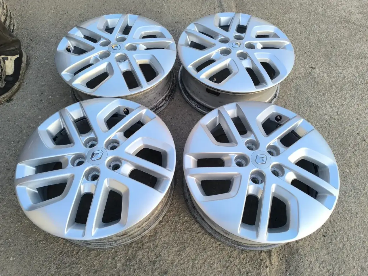 Cztery srebrne felgi aluminiowe z logo Renault, idealne do Nissan Primastar.