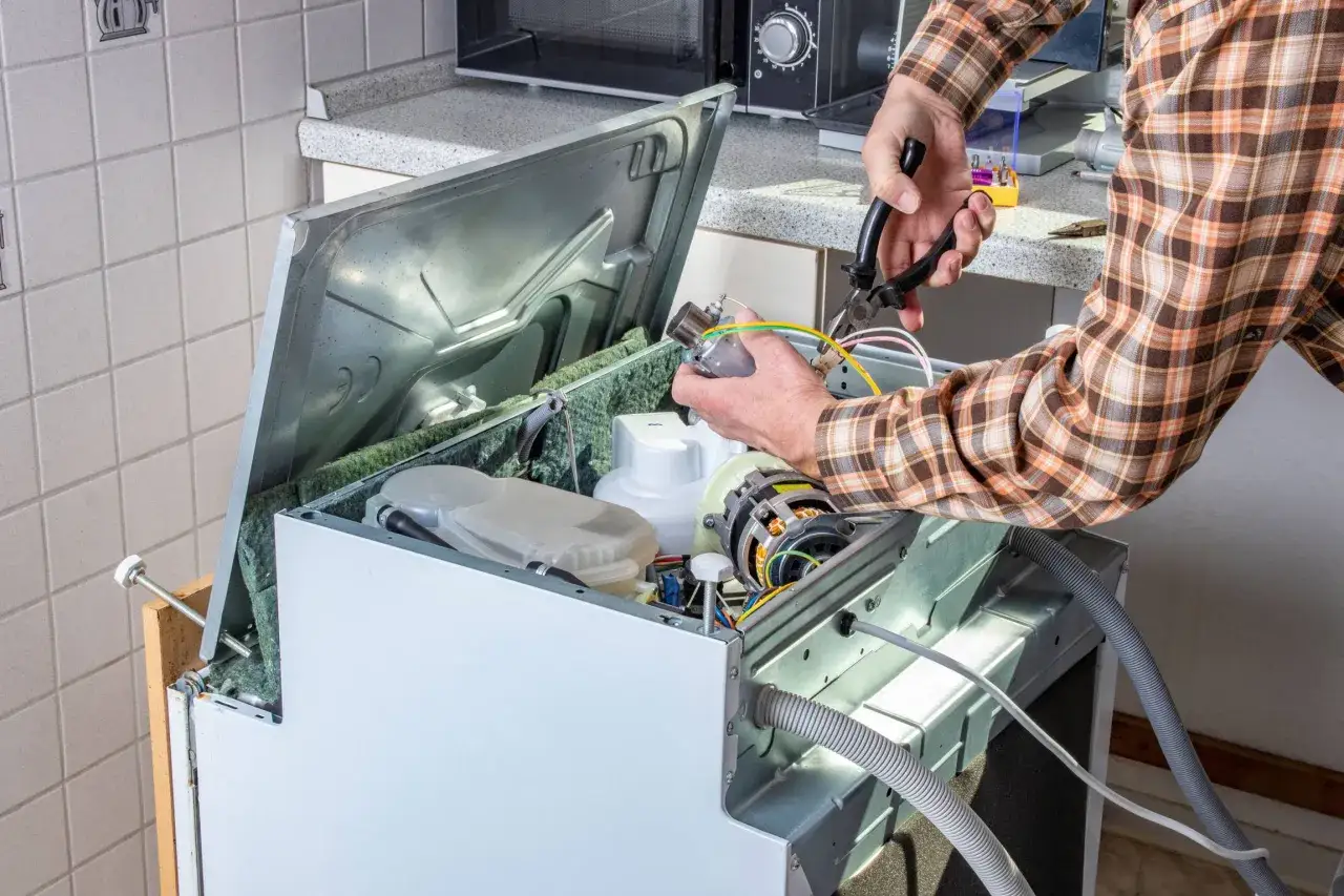 Un technicien répare un four qui ne chauffe plus. Il manipule un composant électrique avec des pinces.