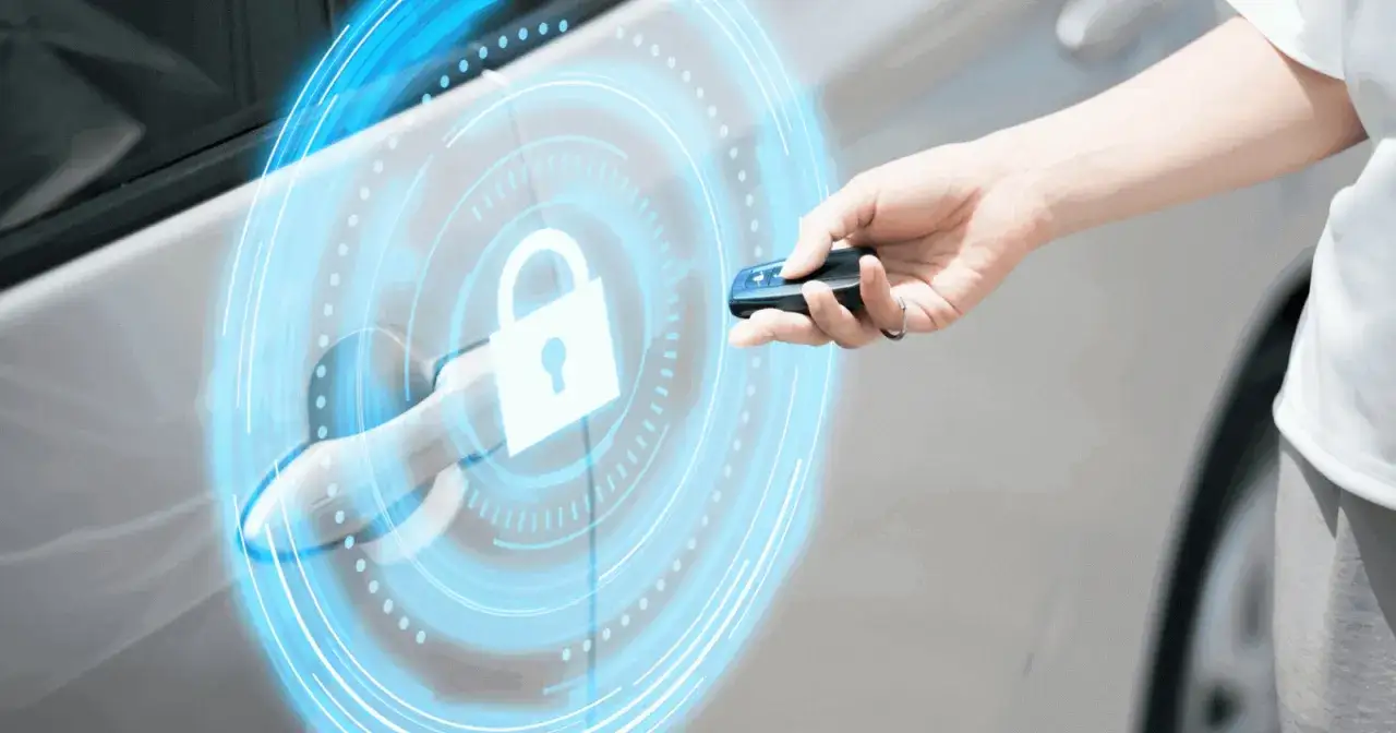 Dłoń z kluczykiem zbliża się do klamki samochodu, aktywując cyfrową tarczę z symbolem kł&oacute;dki. To nowoczesny system keyless entry.