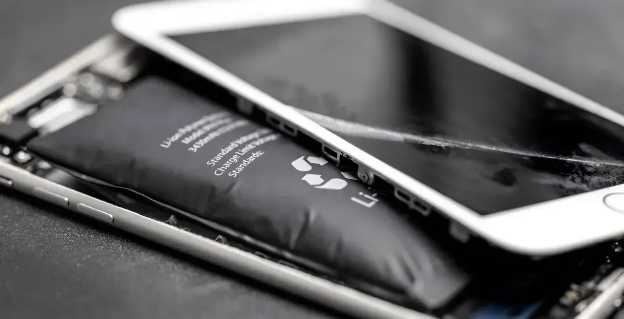 Rozdarty iPhone z widoczną, spuchniętą baterią. Widać jej wybrzuszenie i uszkodzoną obudowę telefonu.