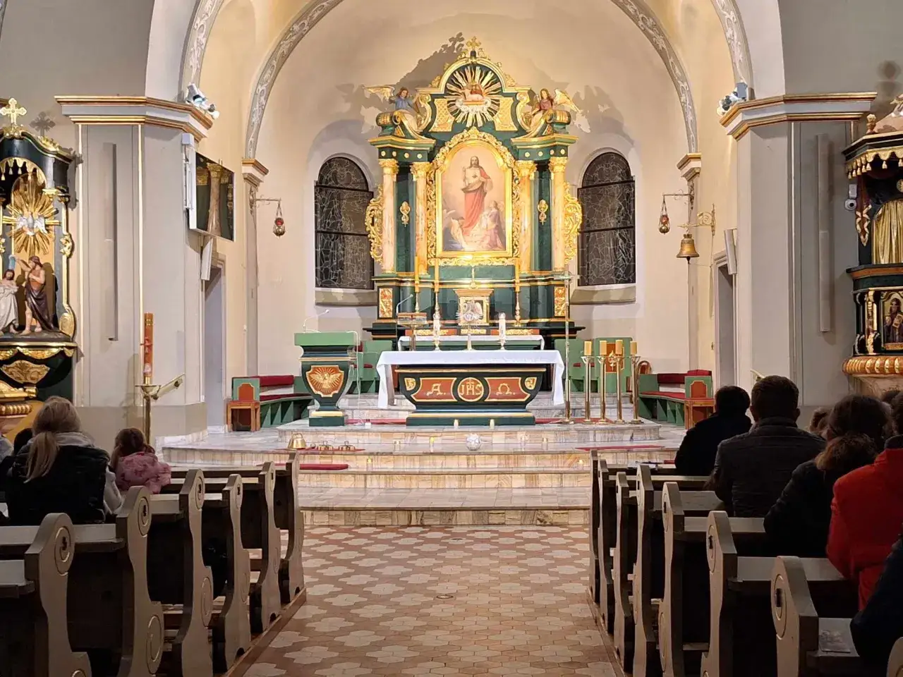 W kościele trwa nabożeństwo. Ludzie siedzą w ławkach, patrząc na ołtarz. To może być pierwszy piątek miesiąca, czas szczególnej modlitwy.