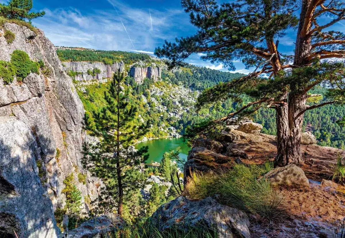 Vista panor&aacute;mica de los picos de Urbi&oacute;n, con un lago verde esmeralda rodeado de bosques y acantilados rocosos.