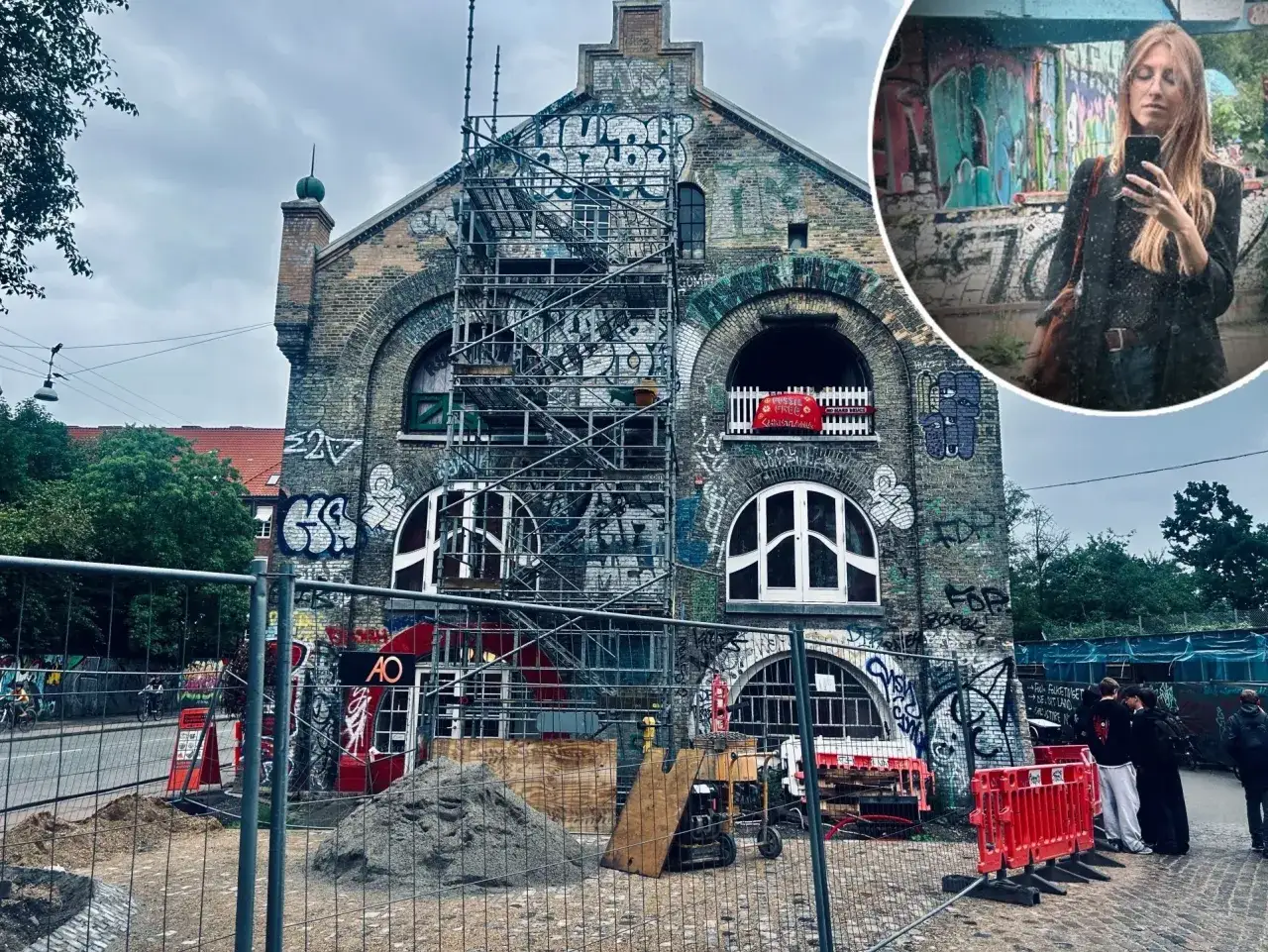 Kopenhaga nietypowe miejsca: zniszczona kamienica pokryta graffiti, w tle kobieta robiąca selfie.
