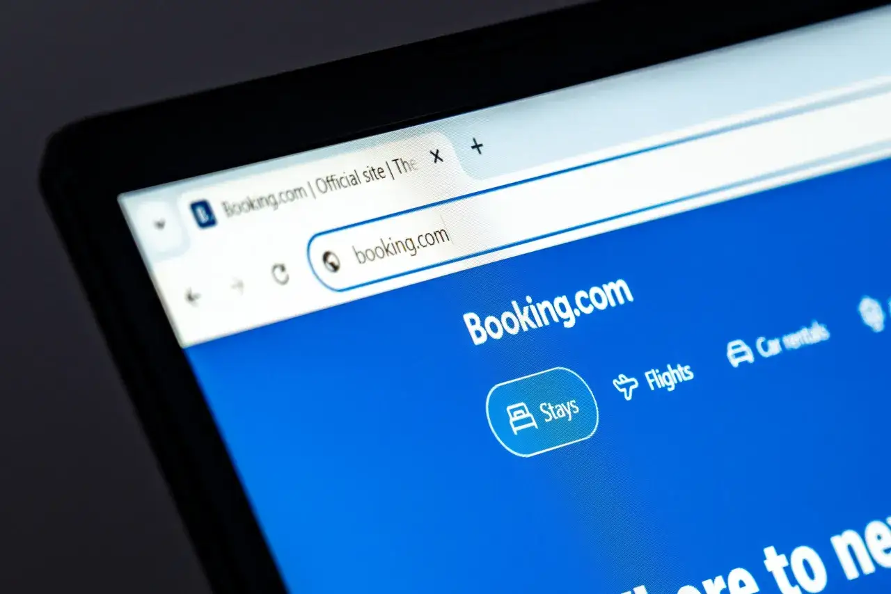 Ekran laptopa z otwartą stroną Booking.com. Czy booking jest bezpieczny? Strona oferuje rezerwację nocleg&oacute;w, lot&oacute;w i samochod&oacute;w.