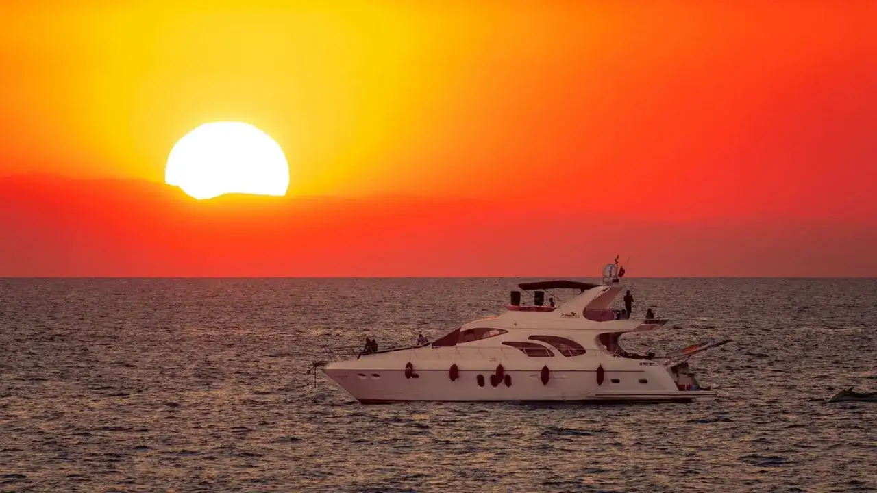 En lyxyacht glider fram p&aring; havet under en dramatisk solnedg&aring;ng. Perfekt f&ouml;r Alanya aktiviteter.