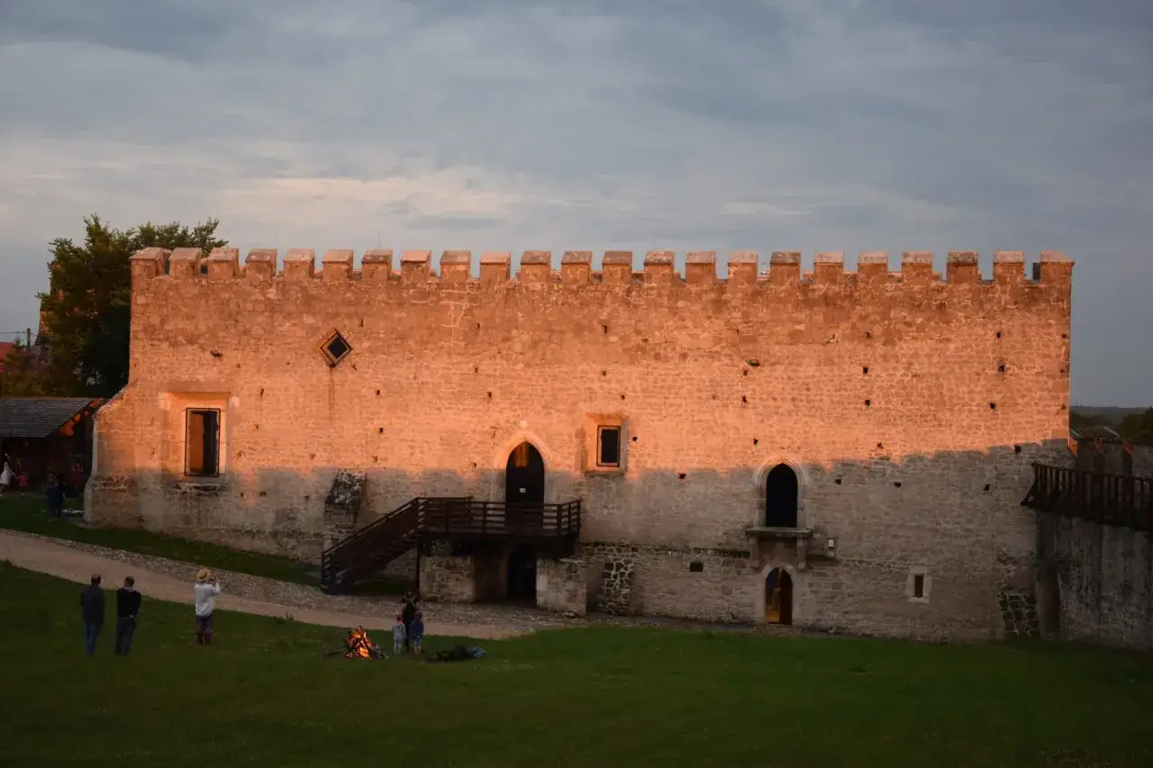 Zachód słońca oświetla mury zamku w Szydłowie, ukazując jego historyczne atrakcje.