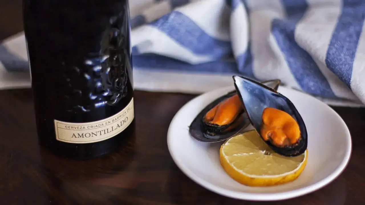 Deliciosos mejillones al vapor servidos con limón y una cerveza Amontillado.