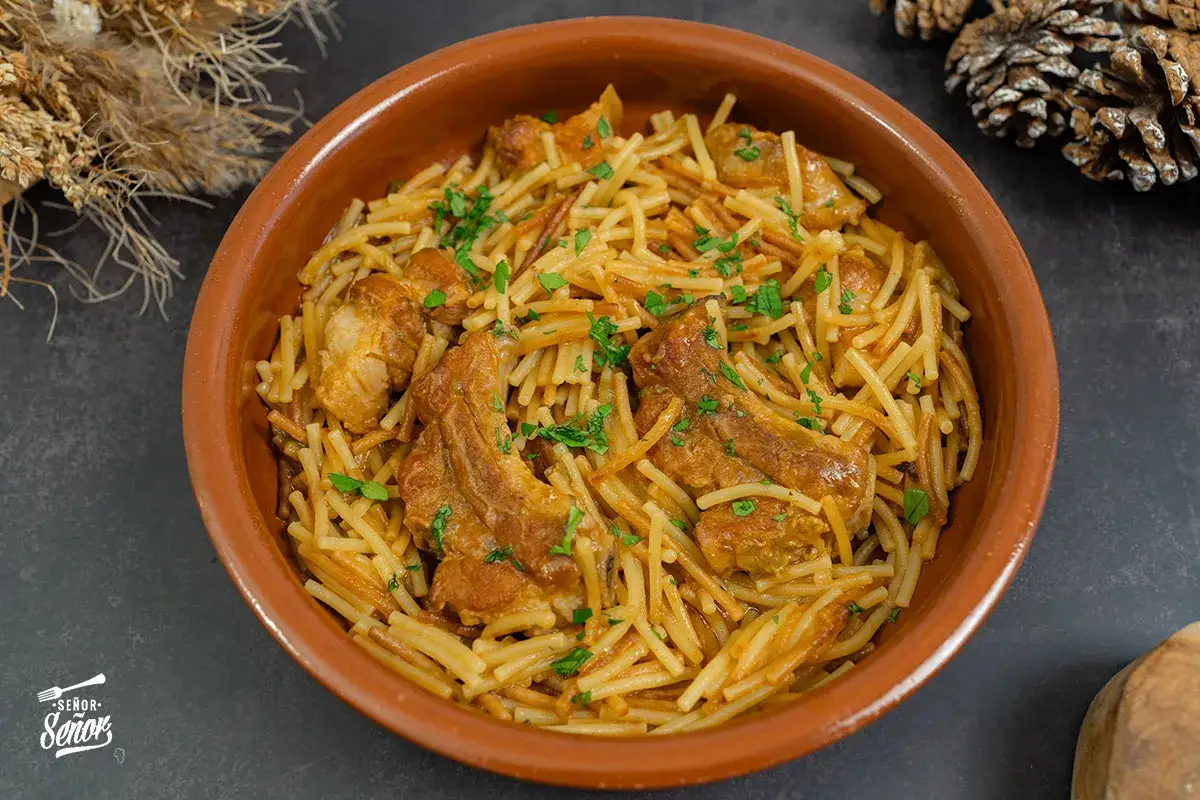Deliciosos fideos a la cazuela con costilla de cerdo, servidos en una cazuela de barro y espolvoreados con perejil fresco.