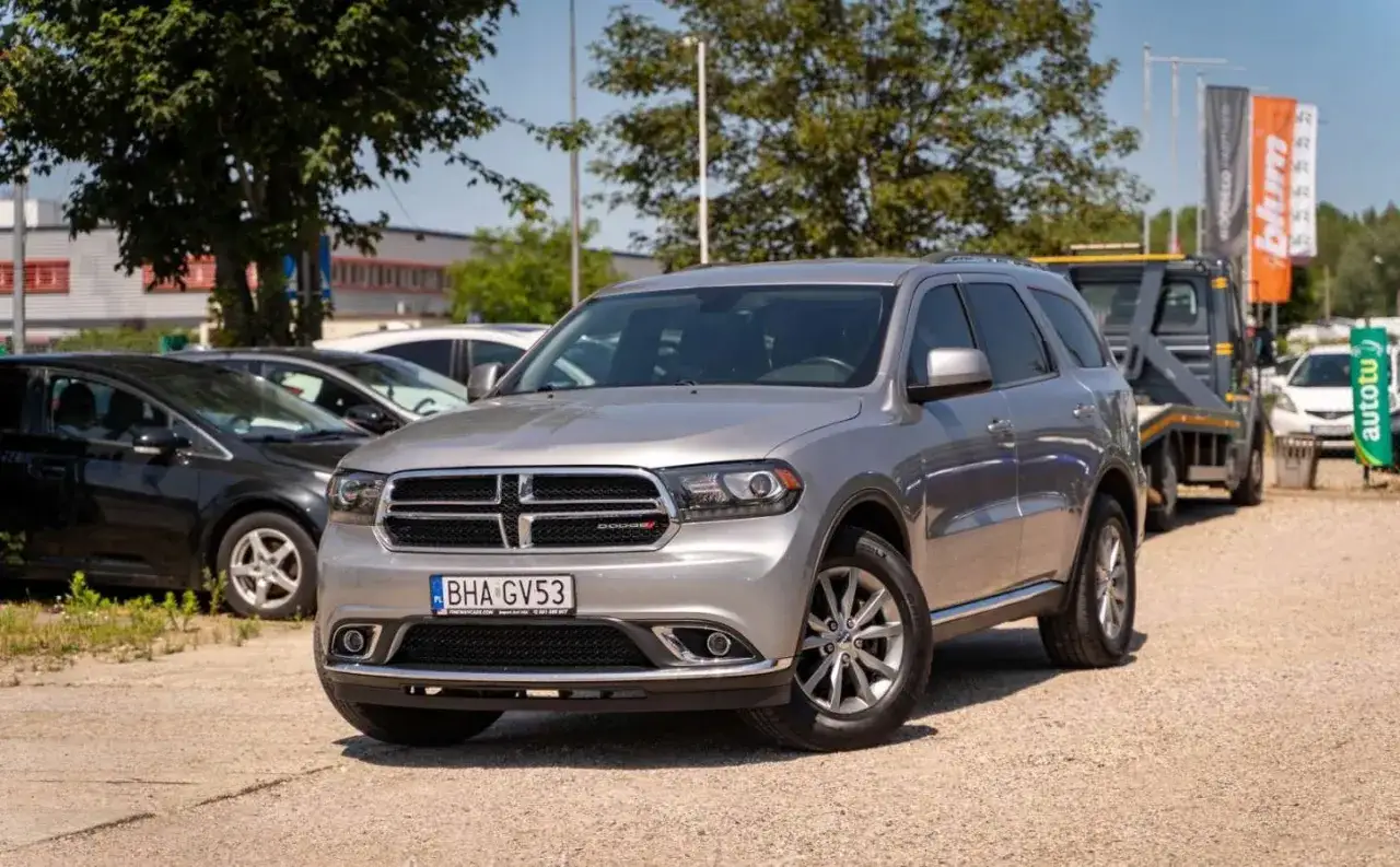 Srebrny Dodge Durango 3.6 gotowy na przygodę. Zaparkowany na placu, czeka na nowego właściciela.