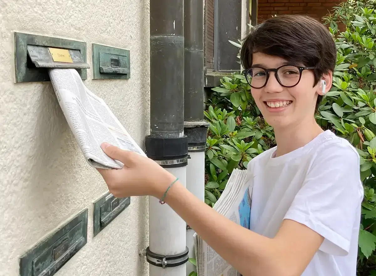 Ein Junge mit Brille liefert Zeitungen aus. Eine tolle Idee, wie man als Kind Geld verdienen kann!