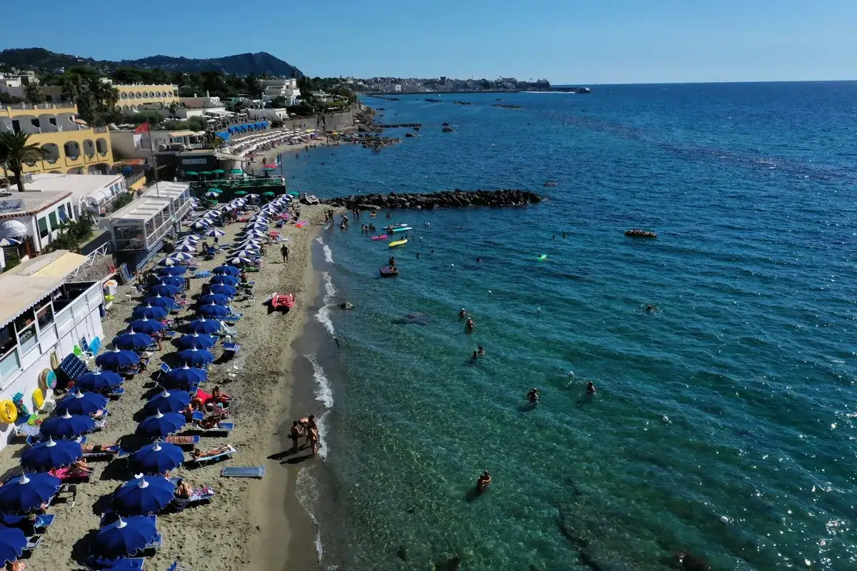 Forio Ischia spiagge: ombrelloni blu, sabbia dorata e mare cristallino animato da bagnanti e gonfiabili.