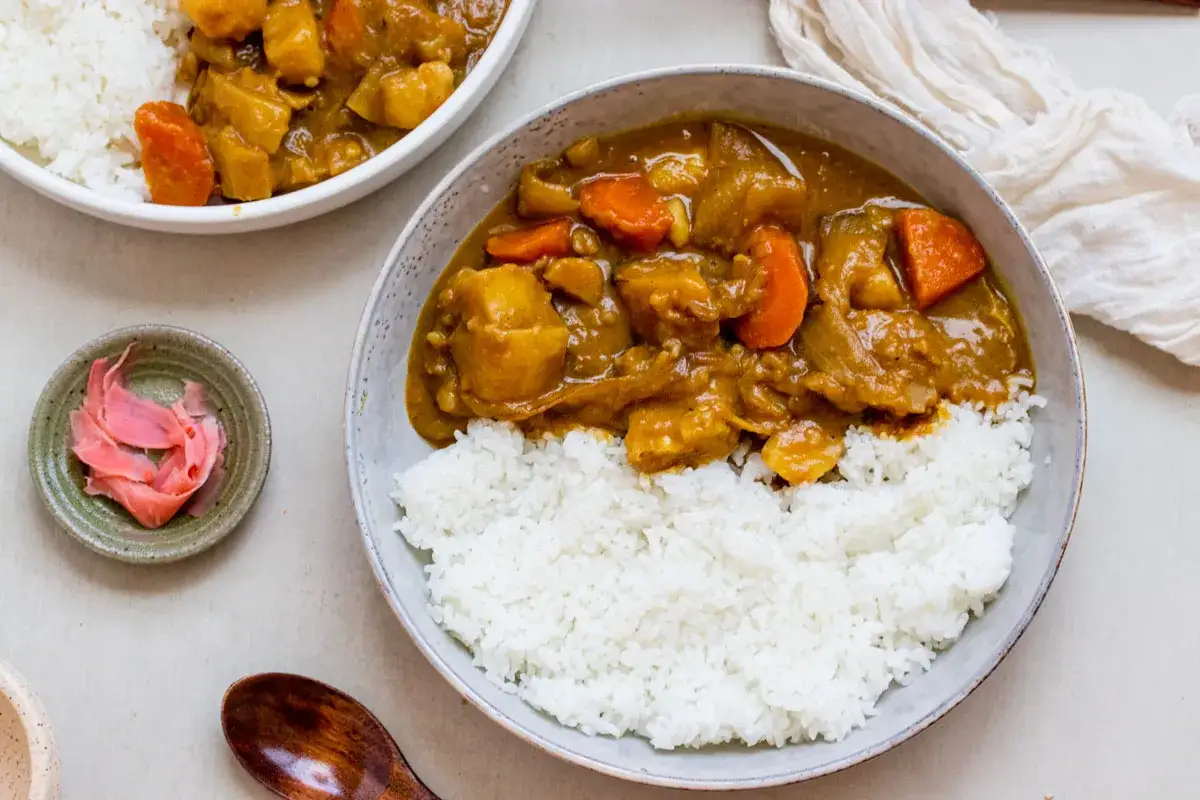 Deux bols de curry japonais savoureux avec du riz blanc et des carottes. Une petite coupelle de gingembre marin&eacute; rose compl&egrave;te ce plat r&eacute;confortant.