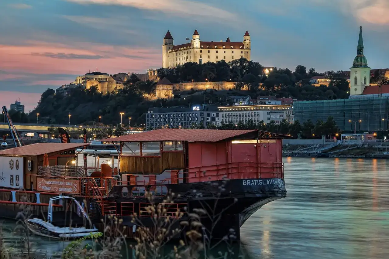 Abendstimmung an der Donau mit Blick auf die Burg Bratislava. Ein Hausboot mit der Aufschrift