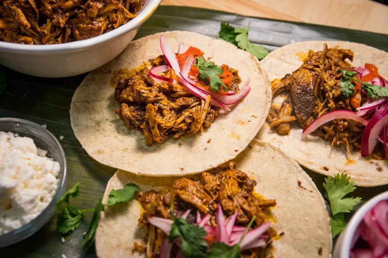 Tacos de cochinita pibil, con cebolla morada y cilantro. Un festín de sabor y tradición.