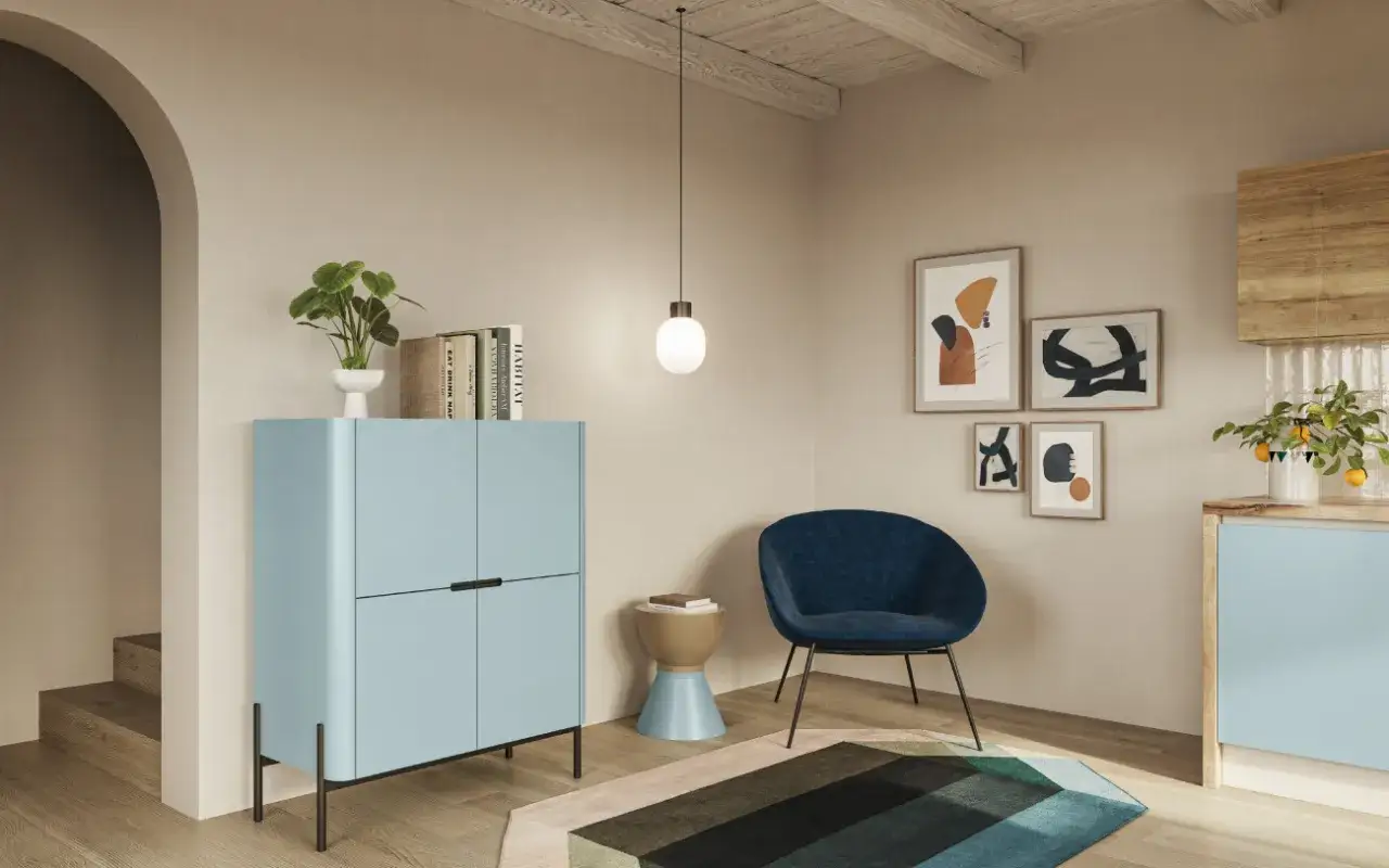 Un angolo lettura accogliente con poltrona blu, tavolino, libreria azzurra e quadri astratti. Ottime idee angolo lettura.