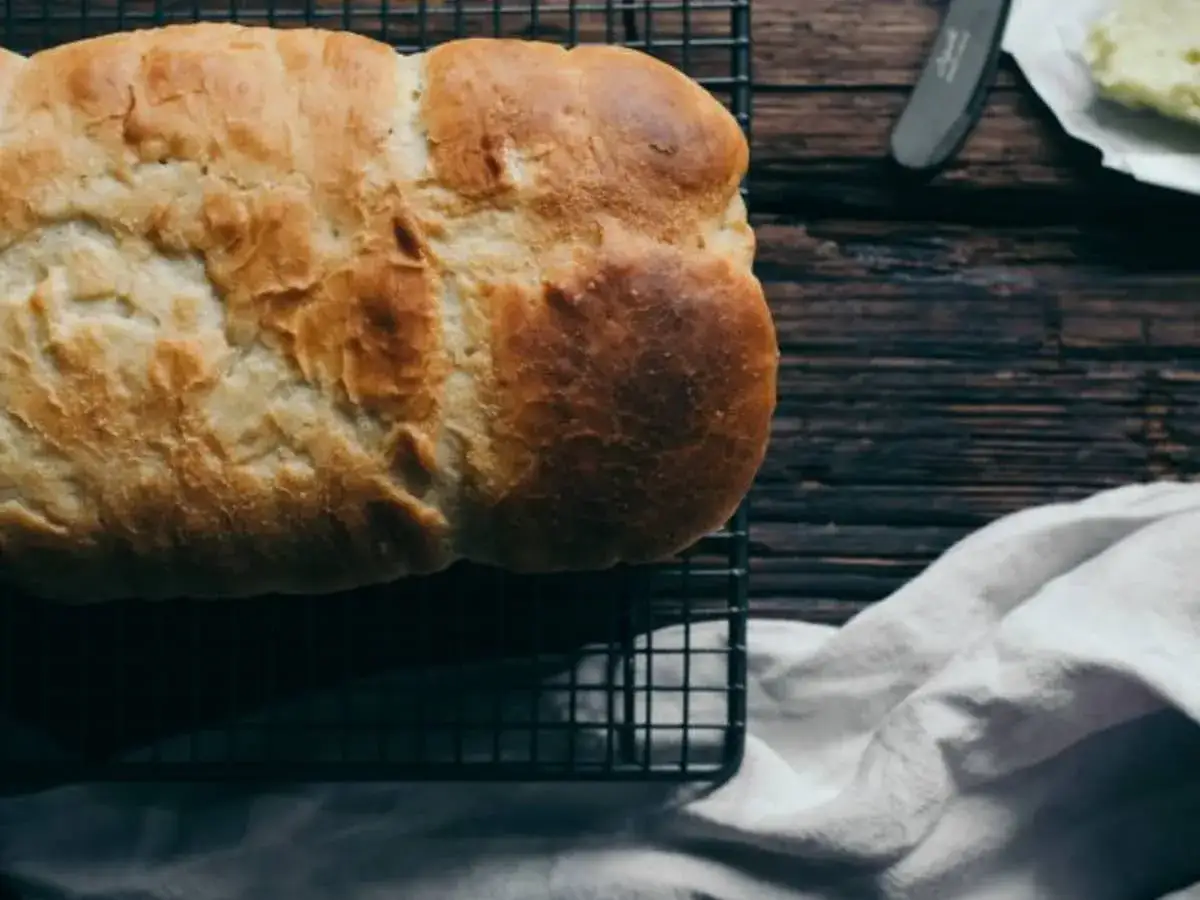 Un pain au levain de gingembre dor&eacute; et croustillant refroidit sur une grille. Une touche de beurre est pr&ecirc;te &agrave; &ecirc;tre tartin&eacute;e.