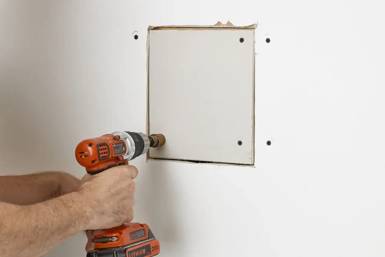 Mano con trapano che crea un buco nel muro, forse un buco nel muro troppo grande per un lavoro di riparazione.