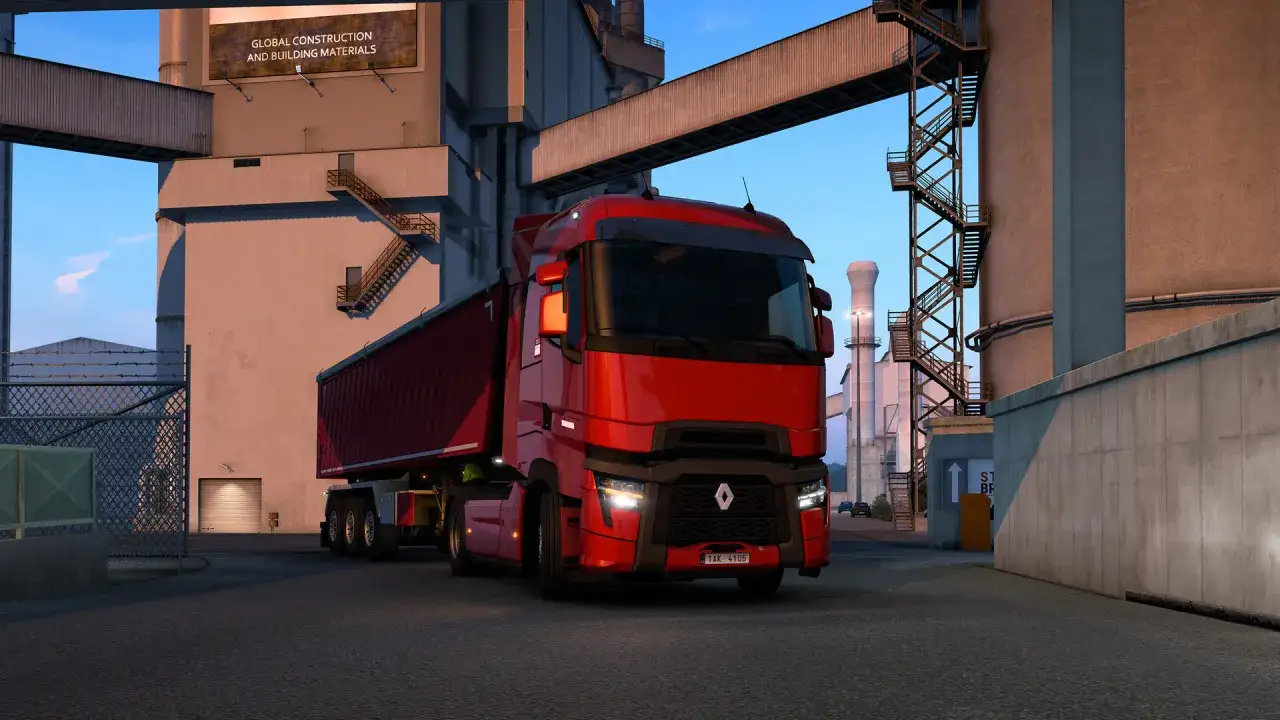 Camión rojo en Euro Truck Simulator 2 PS5, listo para entregar materiales de construcción en una planta industrial.