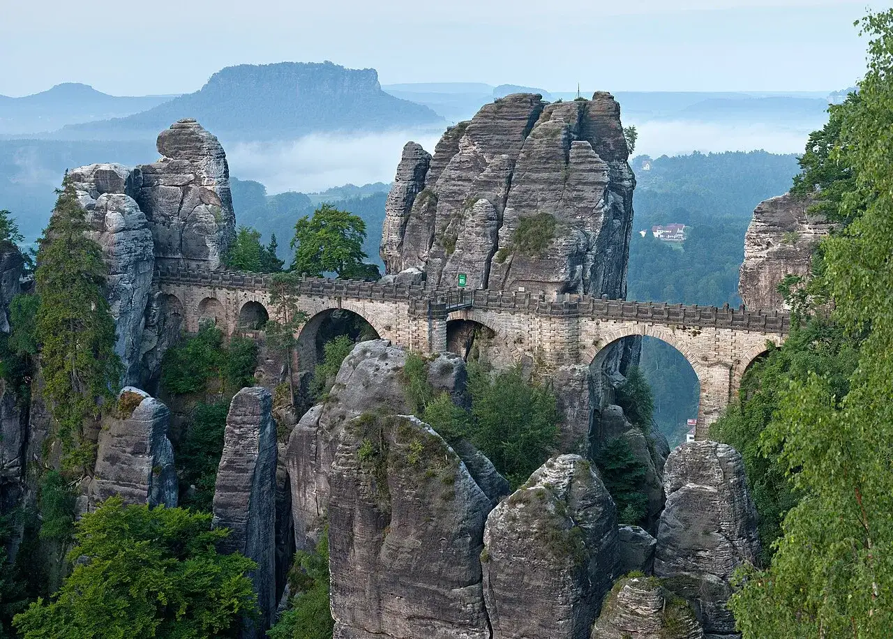 Kamienny most Bastei w skalnym mieście Niemcy, łączący skalne iglice, otoczony mglistym krajobrazem.